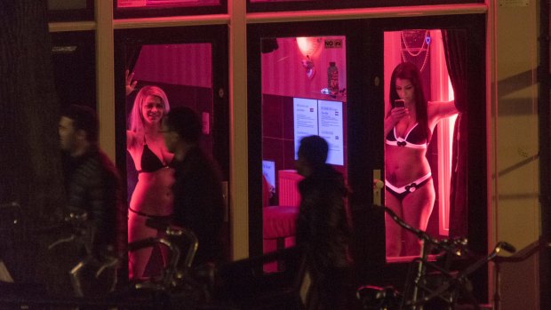 Sex workers are seen behind windows at the red light district in Amsterdam.