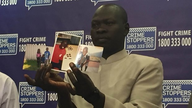 Kuol Atuk's uncle holds photos of the teenager when he was a young boy at Police Headquarters on Tuesday. 
