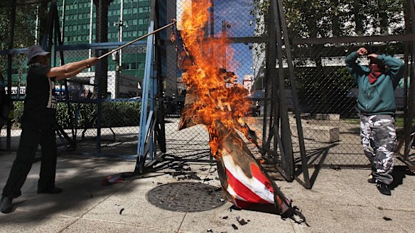 An American flag is set alight in front of the US Embassy in Mexico City on Friday.