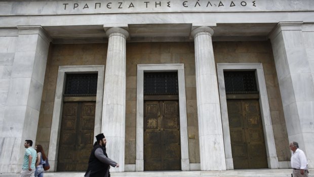A Greek Orthodox priest walks past the headquarters of Greece's central bank, in Athens on Friday.