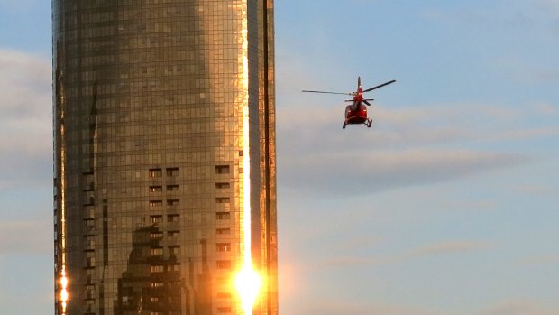 A helicopter flies through Melbourne skyscrapers along the Yarra River.