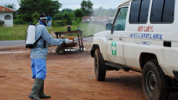 A health worker sprays disinfectant on an ambulance in Nedowein, Liberia on Wednesday.