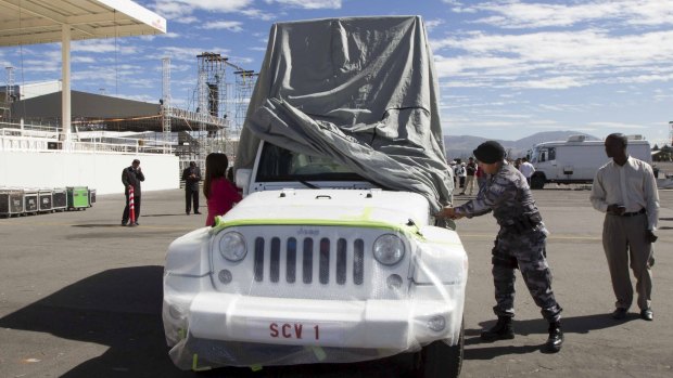 A police officer covers the vehicle to be used by Pope Francis during his visit to Ecuador.