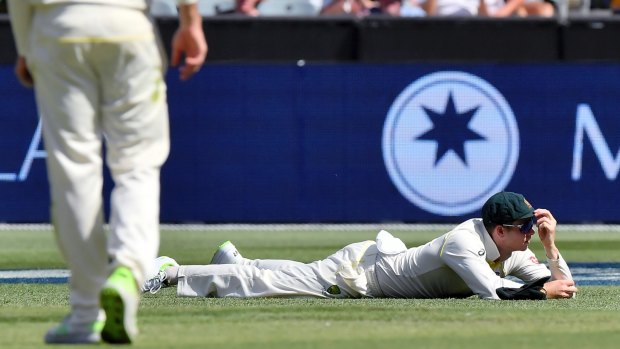 Australia's Steve Smith lays on the ground after dropping Alastair Cook.