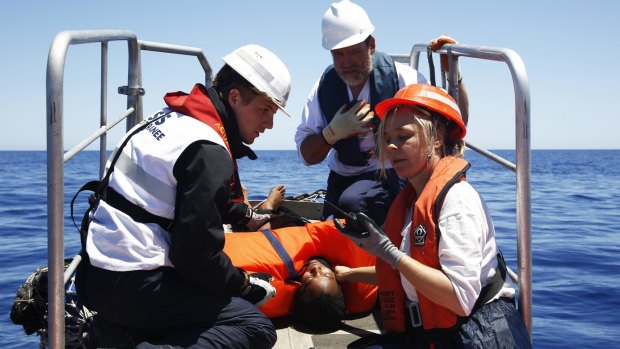 A search and rescue team gives assistance to a migrant rescued from a crowded dinghy in the Mediterranean sea on Monday.