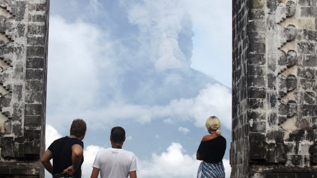 Tourists watch the Mount Agung volcano erupting at a temple in Karangasem.