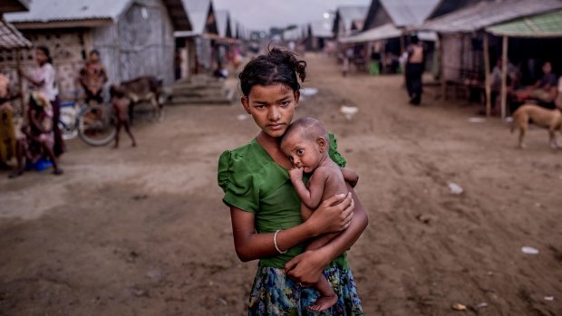 Oma Salema, 12, holds her undernourished brother, one-year-old Ayub Khan, at a camp for Rohingya in Sittwe earlier this month.