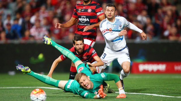 Wanderers goalkeeper Andrew Redmayne dives past a shot at goal by Victory's Kosta Barbarouses.