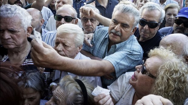 Pensioners queue outside an Athens bank after branches around Greece opened on Wednesday to only allow pensioners to receive a small part of their benefits. 