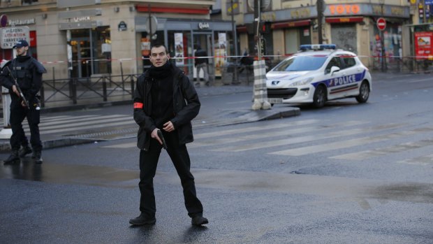 A police officer stands guard near the scene of a fatal shooting of a man armed with a knife and wearing a suspected suicide belt, at a police station in northern Paris.