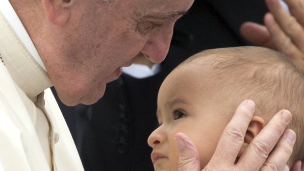 Pope Francis holds a baby at the Vatican earlier this month. 