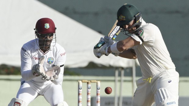 Finding his feet: Australia's captain Michael Clarke plays a shot off West Indies' Jason Holder, as wicketkeeper and captain Denesh Ramdin looks on during the opening day of their first Test match in Roseau, Dominica. 