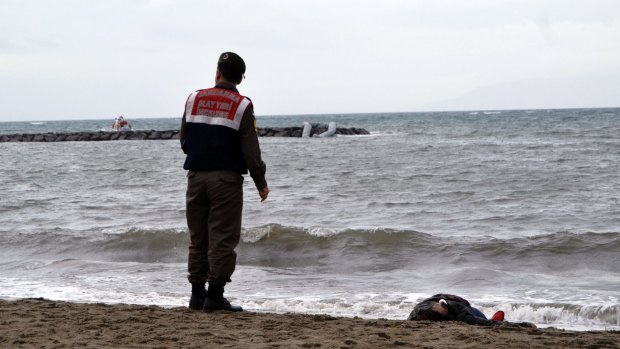 A Turkish paramilitary police officer stands next to the body of a refugee lying on the beach in Ayvalik, Turkey.