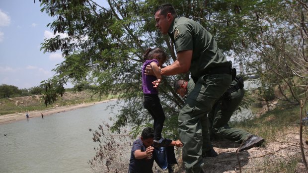US Border Patrol agents in Mission, Texas, help children from El Salvador after they crossed the Rio Grande illegally into the United States last year. 