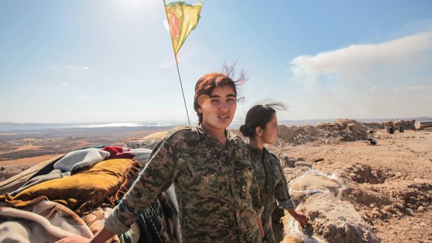 Fighters from the Kurdish People's Protection Units near a checkpoint in the outskirts of the destroyed Syrian town of Kobane, Syria in June. 