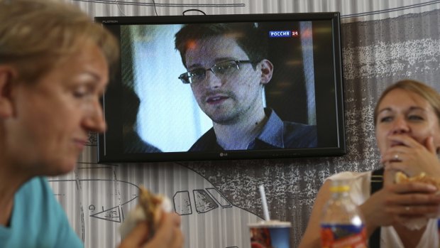 Customers eat at a cafe in Sheremetyevo airport in Moscow as a TV in the background shows an interview with Edward Snowden.