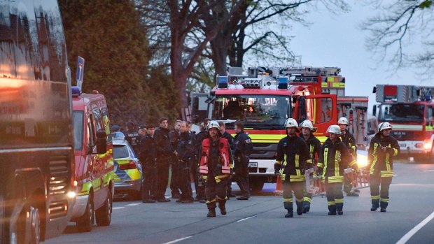 Police officers and firefighters stand outside the Dortmund team bus after it was damaged in an explosion.