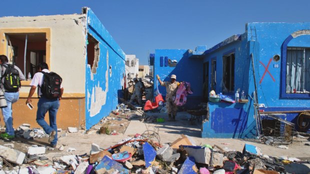 People collect their belongings after a tornado ripped into Ciudad Acuna in northern Mexico, killing at least 13 people on Monday.