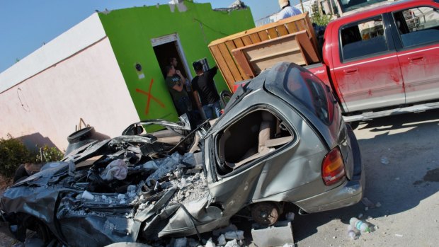 A car lies destroyed in front of a house after a tornado struck in Ciudad Acuna, northern Mexico, on Monday.