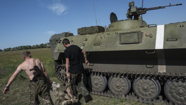Ukrainian servicemen carry a carcass of a sheep past an armoured military vehicle at their positions near Donetsk, in eastern Ukraine on Sunday.