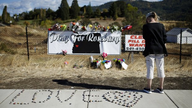 A woman visits a makeshift memorial near the road leading to Umpqua Community College in Roseberg after the mass shooting there.