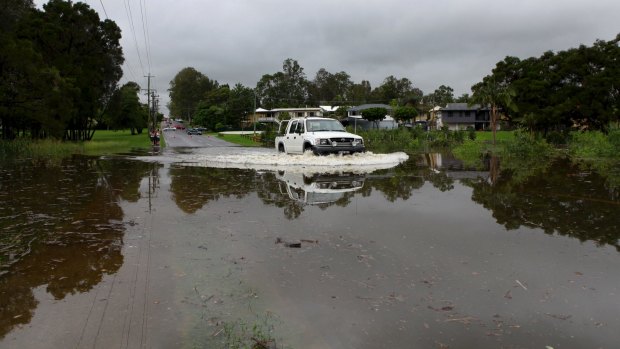 Flash flooding in the Oxley Creek Catchment area in 2012.  A vehicle during the after-school run drives through a swollen Pennywort Creek on Pratten Street, Oxley.