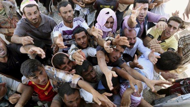 Displaced Iraqis from the Yazidi community gather for humanitarian aid at the Syria-Iraq border last year.