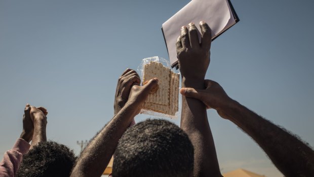 Eritrean and Sudanese asylum seekers hold matzot - traditional Jewish bread - during a celebration of Passover organised by Israeli activists outside the Holot detention centre.