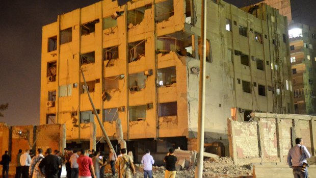 People gather near the scene where a bomb exploded early on Thursday, near a national security building in Shubra el-Kheima, Cairo. 