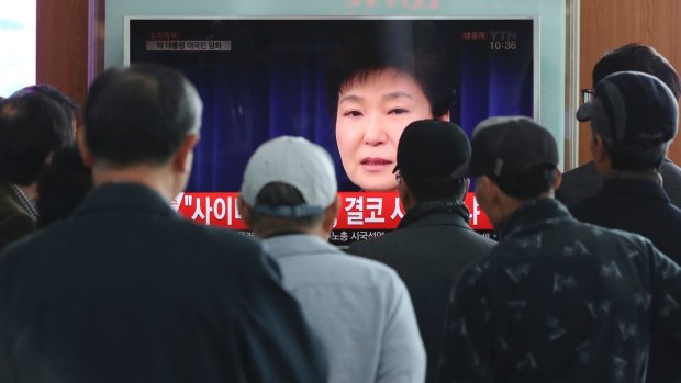 People watch a TV screen showing the live broadcast of South Korean President Park Geun-hye in Seoul on Friday.