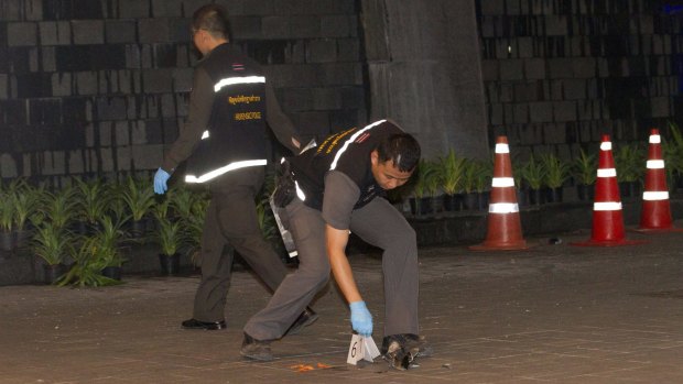 Thai police forensic officers investigate near the front of the Siam Paragon shopping mall, the site of two bomb blasts in Bangkok on Sunday night. 