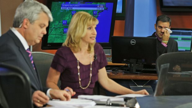 WDBJ-TV7 weatherman Leo Hirsbrunner, right, wipes his eyes during the early morning newscast as anchors Kimberly McBroom, centre, and guest anchor Steve Grant deliver the news at the station on Thursday.