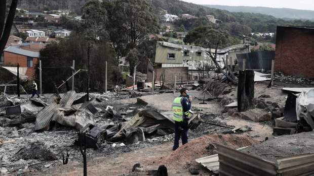 A police officer takes photos of the aftermath of the Tathra bushfires, which destroyed 68 homes.