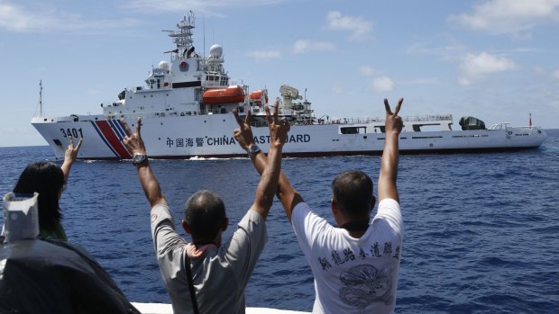 Confrontation: Philippine Marines and a television reporter gesture defiantly to a Chinese Coast Guard vessel after the Philippines successfully resupplied its base on Second Thomas Shoal in the disputed Spratly Islands in March. 