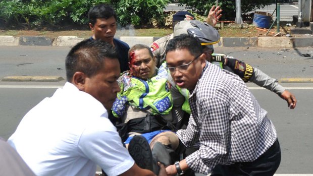 People carry an injured police officer near the site where an explosion went off at a police post during the Jakarta attacks.