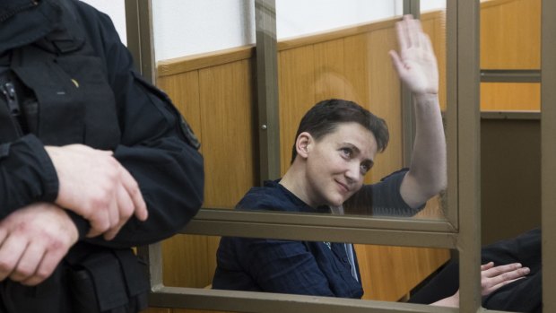 Ukrainian pilot Nadezhda Savchenko waves from a glass cage in court, in Donetsk on Tuesday. 