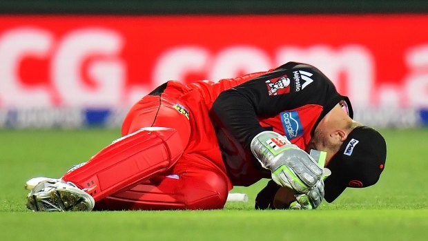 Peter Nevill of the Melbourne Renegades falls to the ground after being struck in the head by the bat of Brad Hodge of the Adelaide Strikers on Monday night.