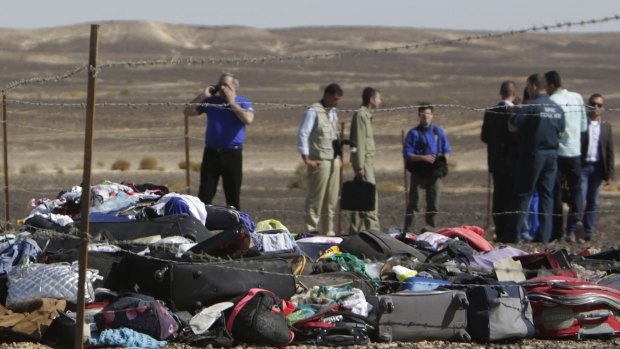 Russian investigators stand near debris, luggage and personal effects at the crash site.