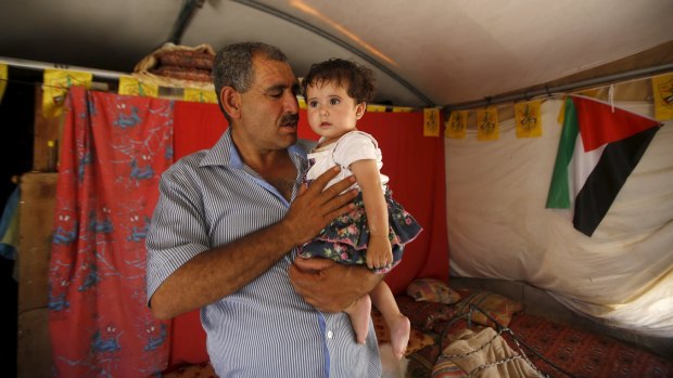 Palestinian man Jihad Nuwaja holds his granddaughter inside his tent in Susiya.