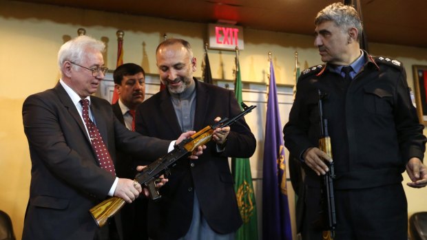 Russian Federation Ambassador Alexander Mantytskiy, left, hands over an AK-47 to Afghan National Security Advisor Mohammad Hanif Atmar, centre, as a symbol of his country's military donation to the Afghan government.