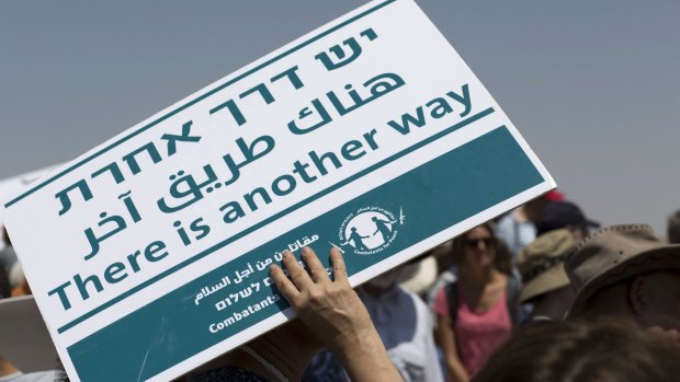 An activist holds a banner of Combatants for Peace during a demonstration at Susiya on Friday, July 24.