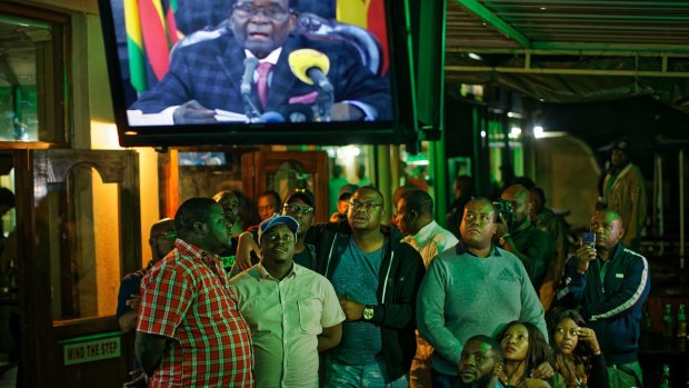 Zimbabweans in downtown Harare gather in a bar to watch Robert Mugabe's televised address to the nation.