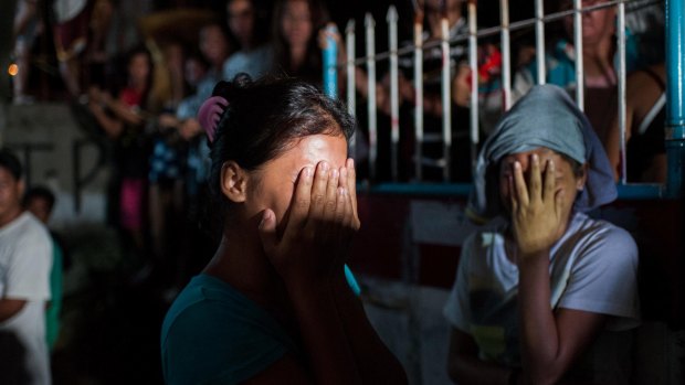 Two women await the fate of their loved ones during an alleged police drug raid on a suspected drug den in Manila. 