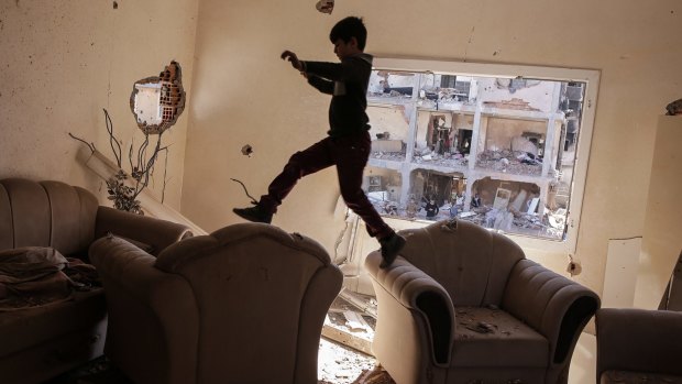 A boy jumps between sofas in his ruined house in Cizre on Wednesday. The curfew was lifted at 5am, allowing residents to return to their conflict-stricken neighbourhoods for the first time since December.