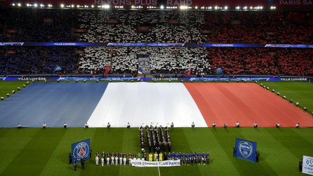 Tribute: A giant French flag covers the pitch as spectators and players hold a banner "We are all Paris" observe a minute of silence for the victims of the Paris attacks, before the French League One soccer match between Paris Saint Germain and Troyes, at the Parc des Princes stadium in Paris.