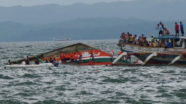 Rescuers help passengers from a capsized ferry. The ferry had just departed the port of Ornoc on Leyte heading to Camotes islands when it was capsized by large waves, the coast guard said.