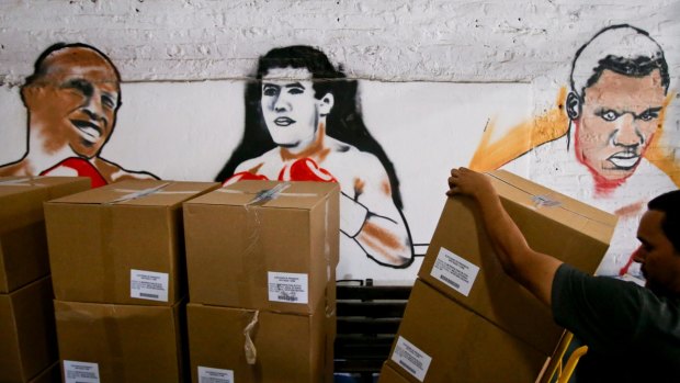An electoral worker unloads boxed election material in the boxing gym inside the National Stadium in Santiago, Chile, on Friday.