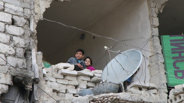 Children peer out from their destroyed home in Aleppo, Syria's largest city.