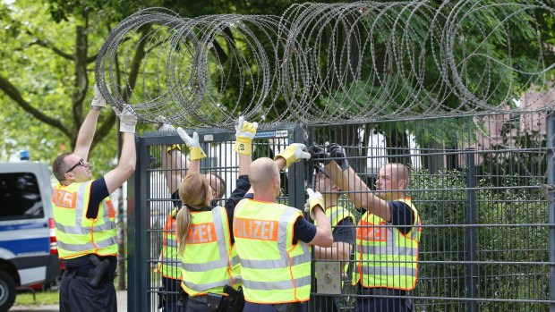 Police officers fix barbed wire on to a fence at the Sternstanze train station close in Hamburg.