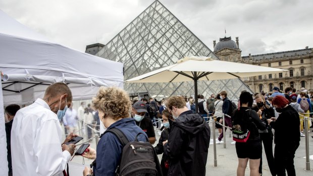 Visitors show their pass to enter the Louvre museum in Paris on Friday. They must show proof of COVID-19 vaccination or a negative test.